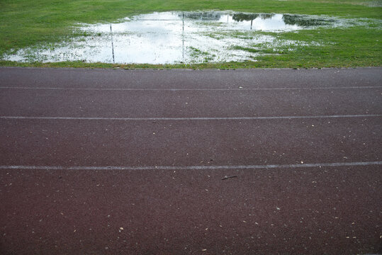 Athletics track after heavy rain with flooded grass, making outdoor training difficult in autumn
