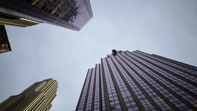 Lit office windows glowing within twilight skyline, warm interior lights puncture cool glass exteriors, metropolitan evening scene with reflective surfaces