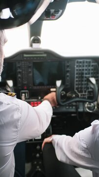 Professional pilot and copilot operating aircraft cockpit controls