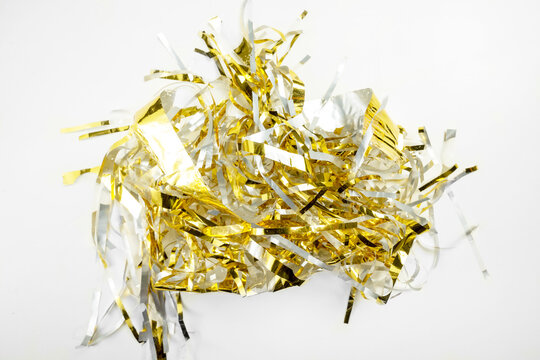 Festive background featuring shiny gold metallic foil tinsel streamers. Holiday or celebration background