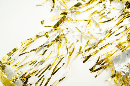 Festive background featuring shiny gold metallic foil tinsel streamers. Holiday or celebration background