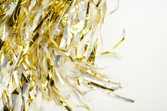 Festive background featuring shiny gold metallic foil tinsel streamers. Holiday or celebration background