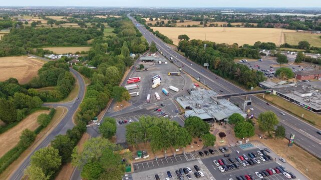 Aerial view of Welcome Break Corley Northbound Services M6 with trucks parked in the lot and traffic on the M6 motorway in Coventry, England, United Kingdom.