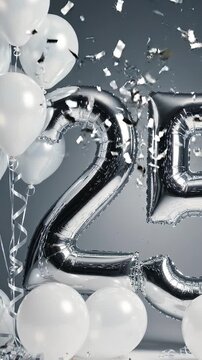 Silver foil balloons shaped as the number 25 surrounded by white balloons and confetti, creating a festive atmosphere for a celebration or anniversary event