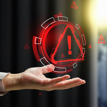Glowing red digital warning hologram floating above a businesswoman hand, representing system error, cybersecurity risk, and hazard alert. Cyber threat concept