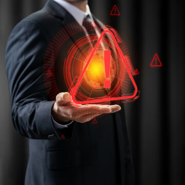 Businessman holding a glowing red holographic warning icon, symbolizing cyber security threat, risk management, system error, or digital alert. Cyber threat concept