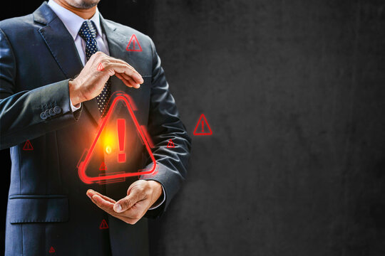 Businessman holding a glowing red holographic warning icon, symbolizing cyber security threat, risk management, system error, or digital alert. Cyber threat concept