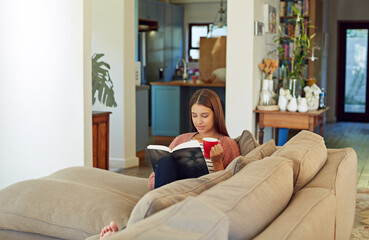 Fototapeta premium Woman, reading and book in home with coffee, fiction story and chapter of best seller fable. Female person, unwind and beverage at house with novel, fantasy storytelling and poetry for stress relief