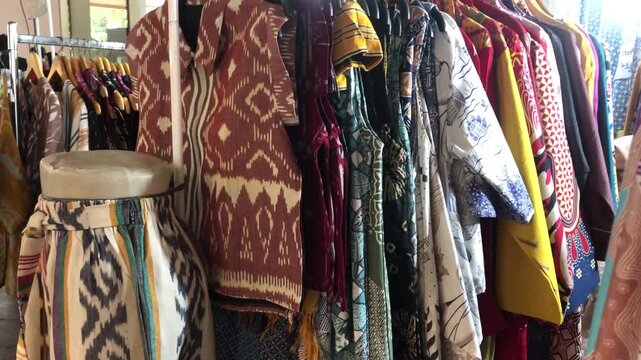Assortment of traditional batik patterned garments hanging on a rack in a boutique shop.