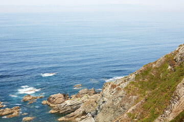 Fototapeta premium High angle view of a steep grassy cliff overlooking the blue ocean in Asturias, Spain