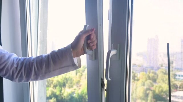 Woman Hand Opening White Plastic Window for Fresh Air and Ventilation in Apartment