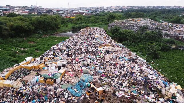 Aerial view of a large waste landfill situated along a dense vegetation in the urban landscape of Ogun State, Nigeria. 