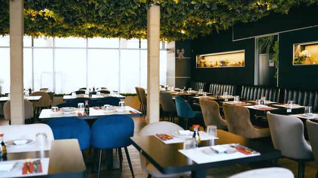 Elegant interior of a contemporary Asian restaurant, ready for service. The room features stylish furniture and a unique ceiling with foliage