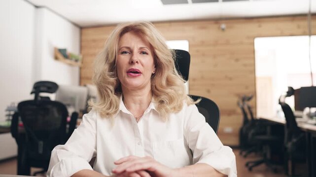 Businesswoman looking at the computer camera during a video call. Middle aged manager talking and gesturing while working in the office