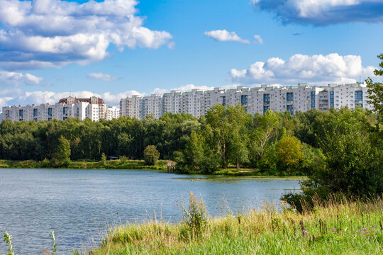 Scenic summer view of Moskva river bank in Strogino district, Moscow, Russia. Residential apartment buildings, green trees, and water landscape.