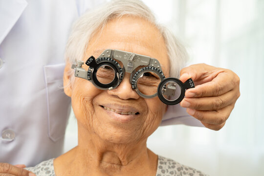 Asian senior woman wearing ophthalmic vision eye test and using optical trial frame.