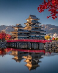 Obraz premium Matsumoto Castle with Red Bridge and Autumn Foliage Reflection