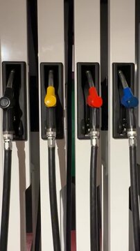 Colorful fuel pump handles aligned on a gas station dispenser arranged vertically