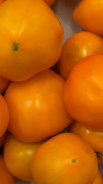 Orange tomatoes closely stacked forming a textured background ideal for food and produce themes