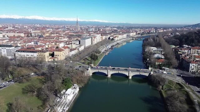 Aerial drone view of Po River, Umberto I bridge, Valentino Park and Mole Antonelliana with snowy Alps in background, Turin, Italy