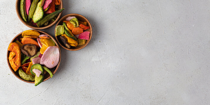 Crispy vegetable chips colorful beetroot, carrot, and sweet potato crisps. Healthy organic snack, natural root veggies, isolated on white, top view copy space banner.
