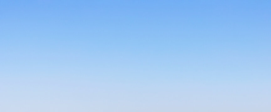 Seamless clear blue sky gradient background featuring a smooth vertical fade from vivid azure to soft pale grey-white, ideal for clean design overlays and digital backdrops.