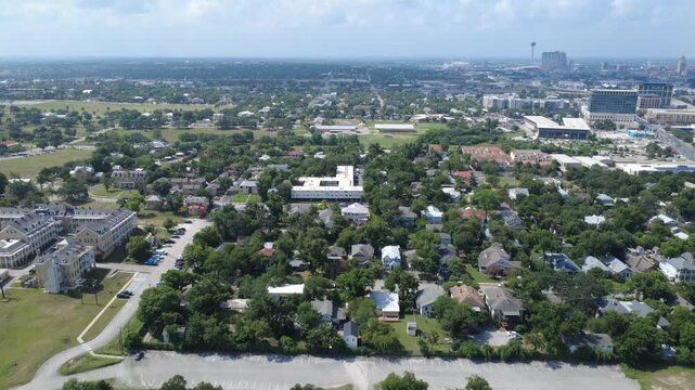 Single family homes cluster near Broadway corridor by Mahncke Park South Texas. Dense foliage surrounds traditional neighborhood streets, multi unit housing blocks, lots, San Antonio