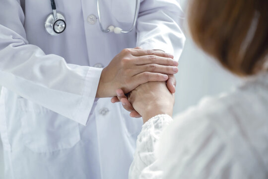Doctor holding hands of patient to give comfort support and reassurance in hospital clinic for medical healthcare compassion concept