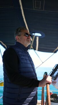 Mature skipper navigating sailboat on a sunny day