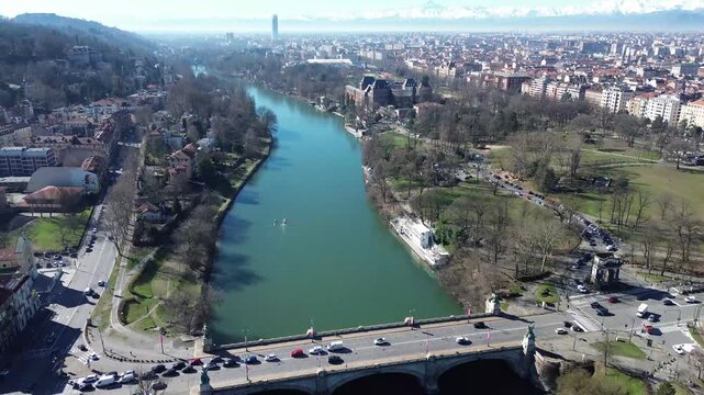 Aerial drone view of Po River, Borgo Medievale and Valentino Park with snowy Monviso mountain in background, Turin, Italy