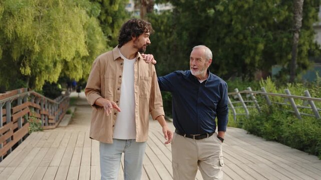 Senior father and his son enjoying a family walk talking, sharing advice, having conversation in a city park