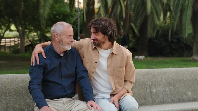 Senior father and son sitting on city bench, supporting, bonding and embracing each other