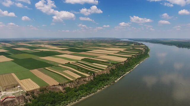 Aerial view of the Danube River flowing past agricultural fields and cliffs in Serbia.