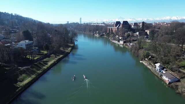 Panoramic drone shot over Po River and Valentino Park looking towards Monviso peak and Alps, Turin, Italy