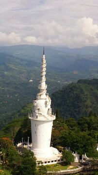 Aerial drone of tall Ambuluwawa tower is stylized from Buddhist stupa, Hindu kovil, Muslim mosque, and Christian church altogether. Gampola, Sri Lanka. Vertical video.