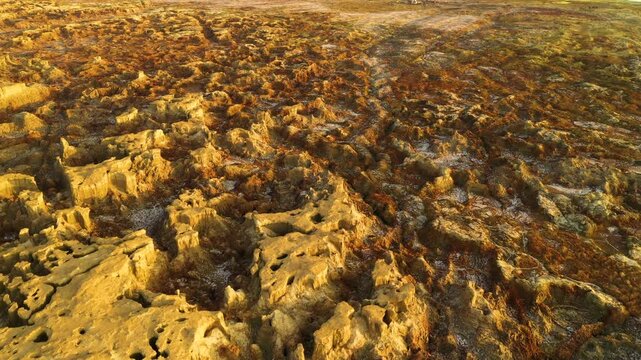 Aerial view of the rugged geothermal area with vibrant yellow and brown mineral deposits and salt formations in Dalol, Afar, Ethiopia.