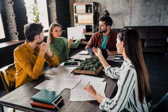 Business meeting with colleagues collaborating around a table, presenting documents and discussing project ideas and strategy in a modern loft office