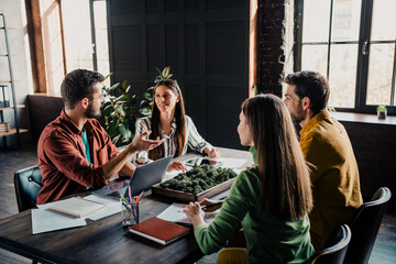 Young team collaborating in an informal office meeting around a table with laptop, notes and...