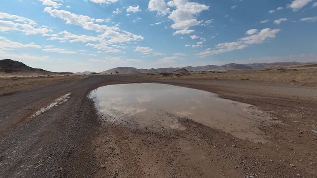 Puddle of water on the road, a road in Namibia, dangerous water