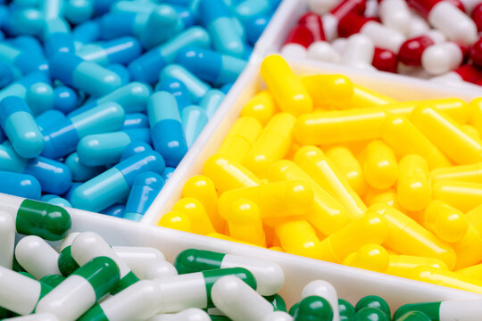 Selective focus on green-white capsule pills on blurred yellow, blue, red-white capsules pill. Drug selection for reasonable use in hospital. Pharmaceutical industry. Pharmaceutical business. Pharmacy