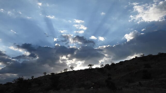 Morning sun rays breaking through the clouds, African landscape. Timelapse.
