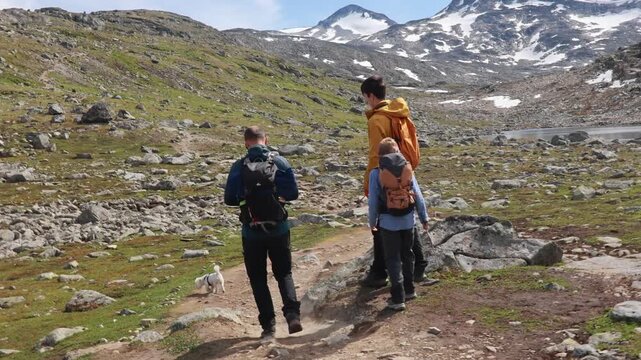 Beautiful european family with children and pet dog, hiking Kyrkja mountain on a beautiful sunny summer day, sunset, snow, lakes, valley
