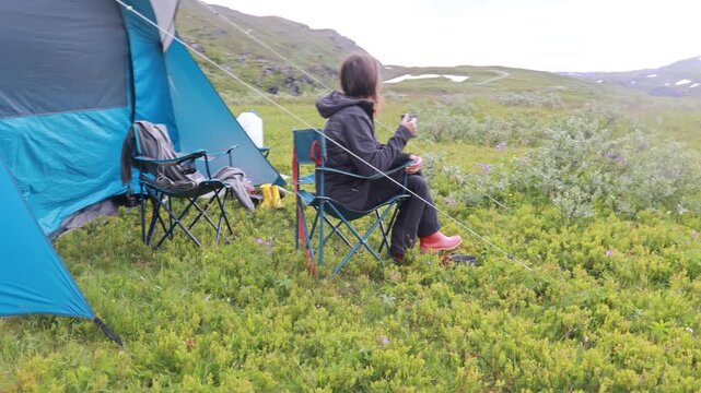 Child, cute boy, brushing his teeth in front of a tent in the morning in a beautiful Norway nature, grass, mountains, flowers, anazing nature