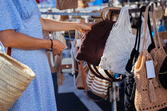 Mature Woman Choosing Crochet Handbag Among Handmade Accessories at Spanish Market