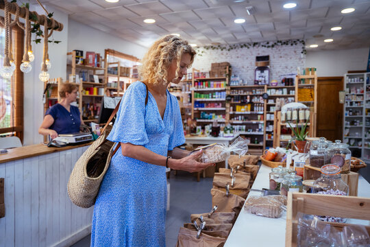 Mature Woman Choosing Packaged Artisan Bread in Natural Food Store During Shopping in Spain