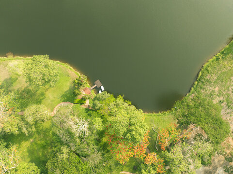 Aerial drone view of a lakeside garden at a tropical wellness retreat. Small dock and boats beside calm water. Eco travel, resort leisure, and nature escape concepts. Wellness tourism and relaxation.