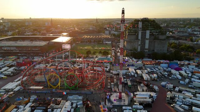 Hamburg, Germany - 24 August 2026: Aerial view of Hamburger Dom fairground with roller coasters and a tall swing ride at sunset.