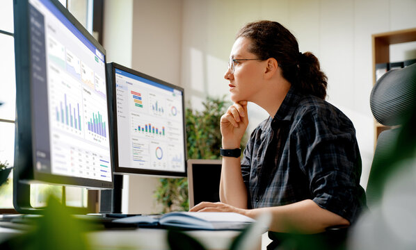 Focused Data Analyst Working with Analytics Dashboard on Dual Monitors