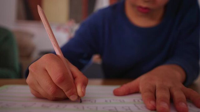 Child practices writing letters by hand in a workbook at home, improving handwriting, pencil control, alphabet recognition and early literacy through focused independent learning