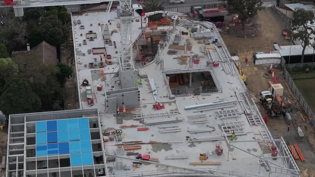 Croydon, Australia - 25 August 2026: Aerial view of a construction site with a tower crane, steel beams, and workers on the concrete roof deck.